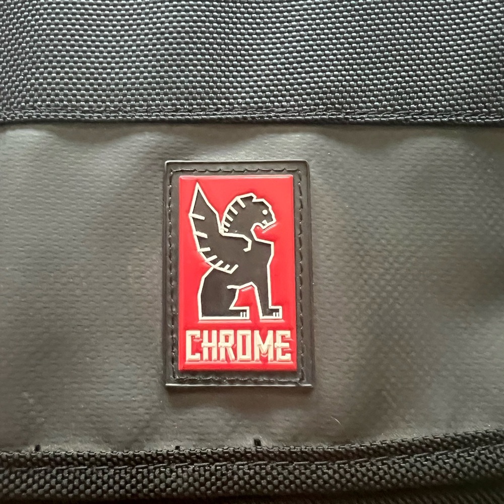 Chrome backpack with crossbody seat belt buckle closer.